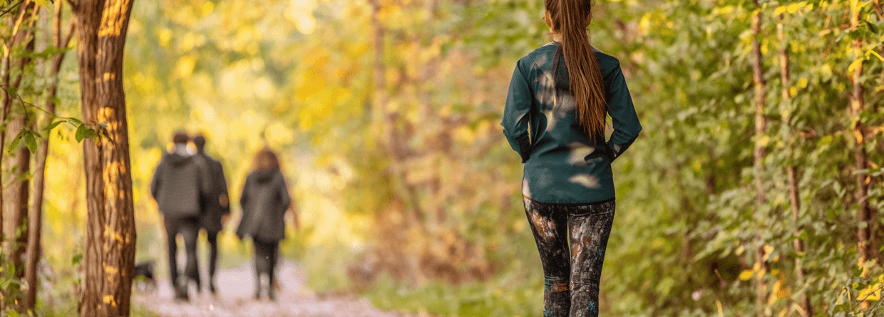 Vrouw loopt in een bos met een groepje mens met hond voor haar uit