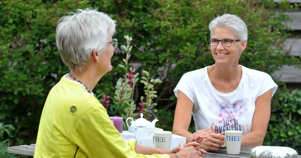 Een vrouwelijk stel dat samen buiten aan een picknicktafel zit