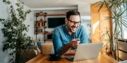 Man achter laptop in thuisomgeving