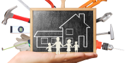 Afbeelding van een getekend huis met mensen op een krijtbord met daarom heen klus gereedschap