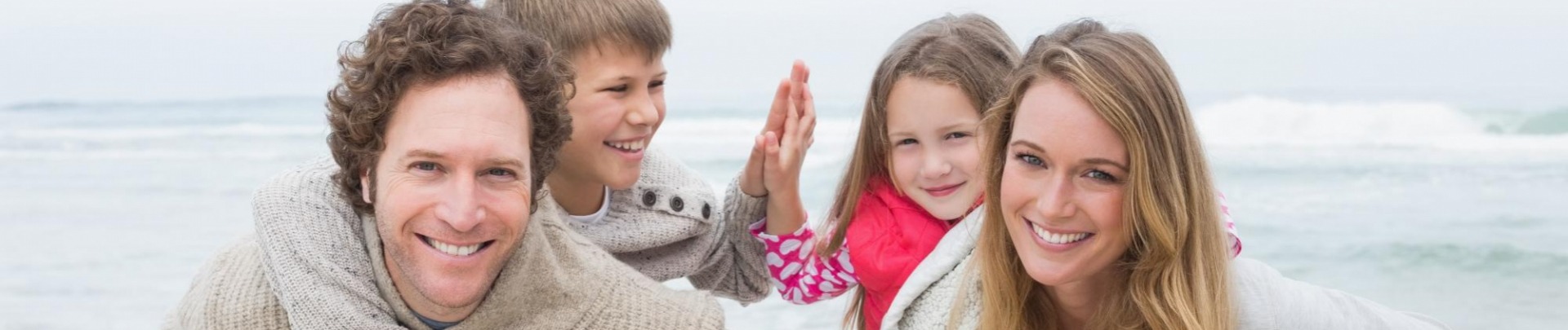 Gezin op het strand ouders met kinderen op hun rug